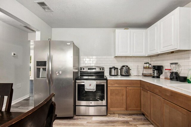 kitchen featuring white cabinetry, sink, backsplash, and light wood-type flooring