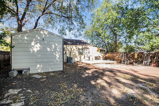 back of property with central AC unit and a patio