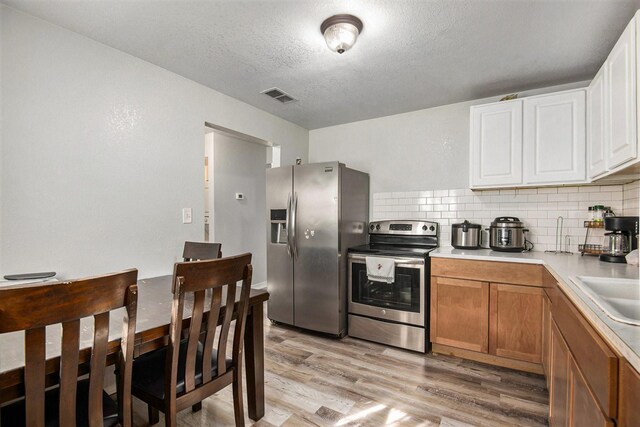 kitchen with backsplash, light hardwood / wood-style floors, sink, and white cabinets