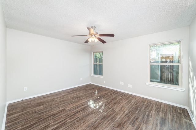 empty room with dark hardwood / wood-style floors, a textured ceiling, and a wealth of natural light
