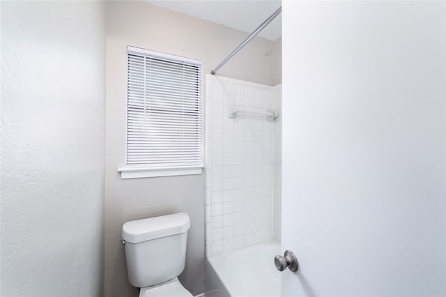 bathroom featuring toilet and tiled shower / bath