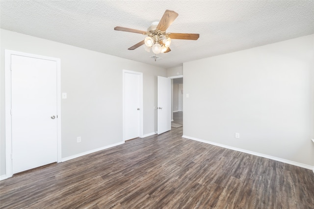 empty room featuring ceiling fan, dark wood-type flooring, and a textured ceiling