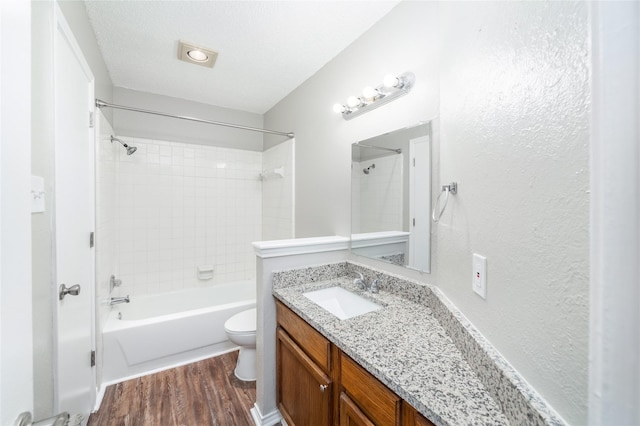 full bathroom with vanity, tiled shower / bath combo, toilet, a textured ceiling, and wood-type flooring