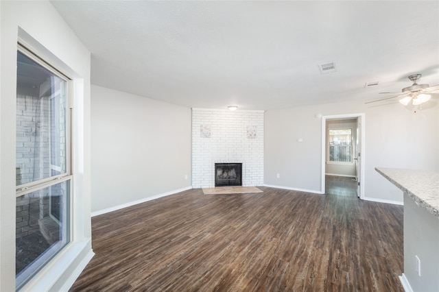 unfurnished living room with a fireplace, dark hardwood / wood-style floors, and ceiling fan