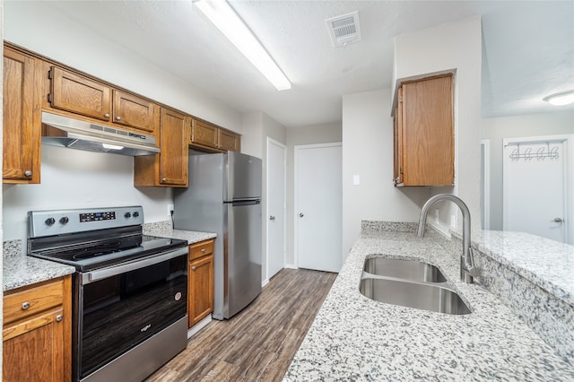 kitchen with sink, a textured ceiling, light stone counters, dark hardwood / wood-style flooring, and stainless steel appliances