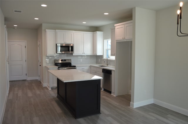 kitchen featuring light hardwood / wood-style floors, a kitchen island, white cabinetry, and stainless steel appliances