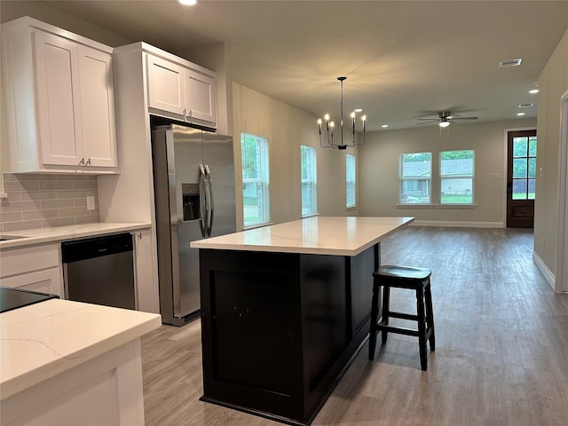kitchen with white cabinets, appliances with stainless steel finishes, light wood-style flooring, recessed lighting, and decorative backsplash