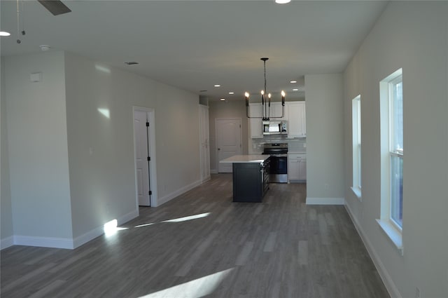 kitchen with appliances with stainless steel finishes, baseboards, wood finished floors, and white cabinets