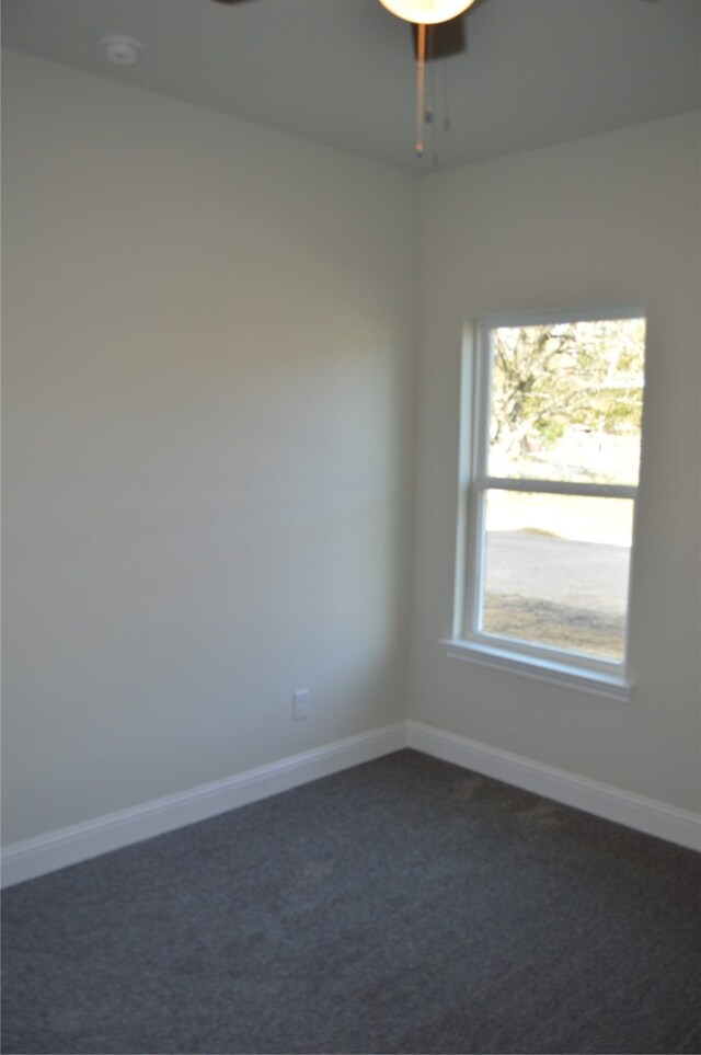 spare room with dark colored carpet and ceiling fan