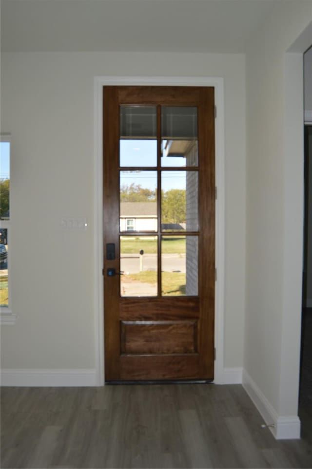 doorway featuring baseboards and wood finished floors