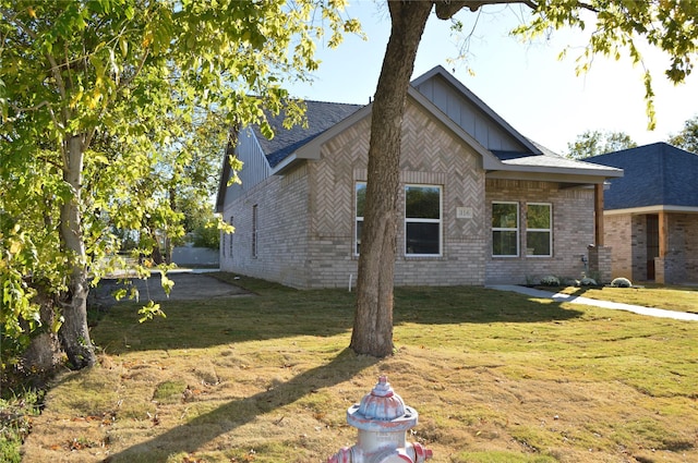 view of home's exterior with brick siding, board and batten siding, and a yard