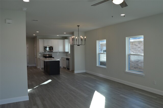 kitchen featuring appliances with stainless steel finishes, dark wood-type flooring, white cabinets, a kitchen island, and hanging light fixtures