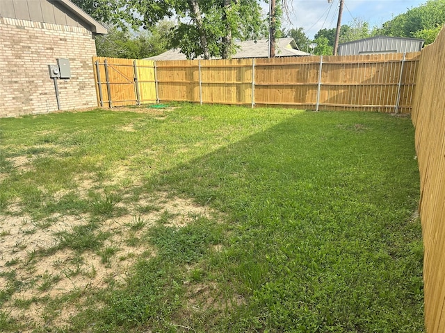 view of yard with a fenced backyard and a gate