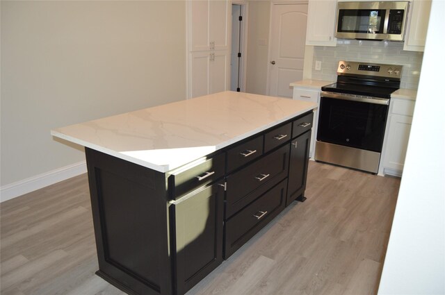 kitchen featuring a center island, white cabinets, light hardwood / wood-style floors, and appliances with stainless steel finishes