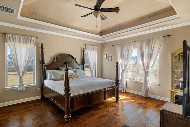 bedroom with ceiling fan, a tray ceiling, dark hardwood / wood-style flooring, and ornamental molding