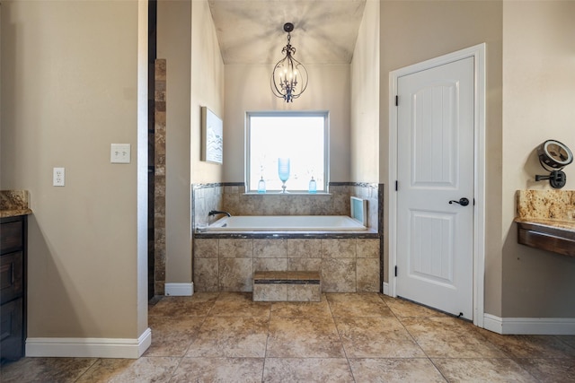 bathroom with tile patterned floors, tiled bath, a notable chandelier, and vanity