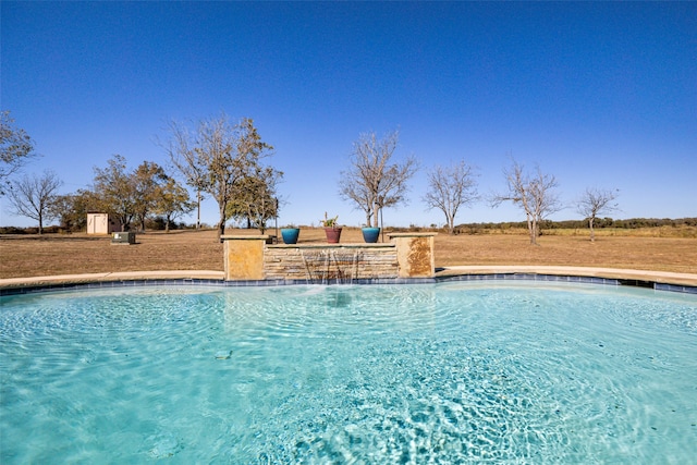 view of pool with pool water feature and a lawn