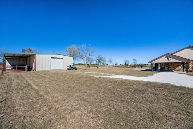 view of yard featuring a garage, an outbuilding, and a carport