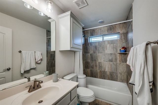 full bathroom featuring vanity, a textured ceiling, tiled shower / bath combo, and toilet