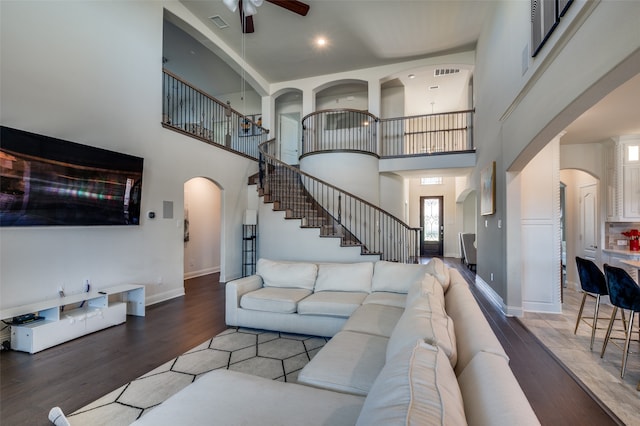 living room with ceiling fan, hardwood / wood-style floors, and a high ceiling