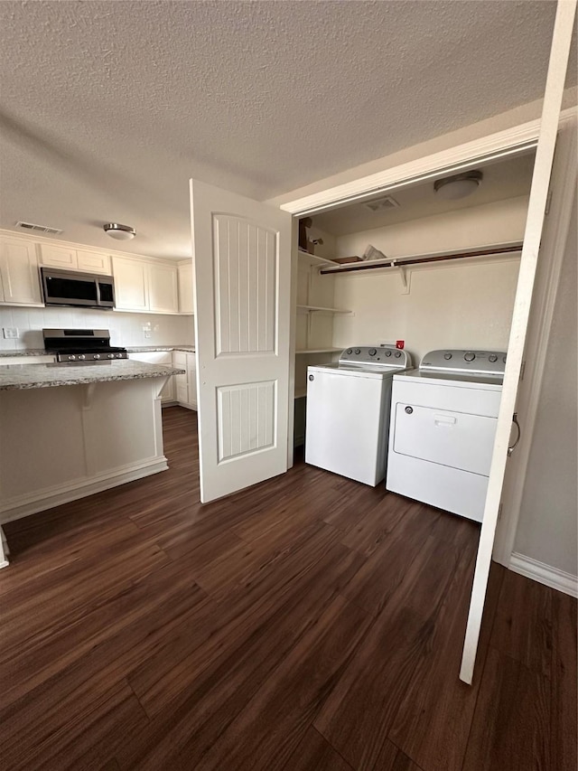 kitchen featuring washer and clothes dryer, white cabinetry, dark hardwood / wood-style flooring, and stainless steel appliances