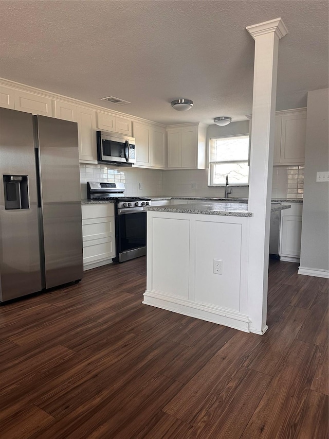 kitchen with decorative backsplash, dark hardwood / wood-style flooring, white cabinetry, and stainless steel appliances