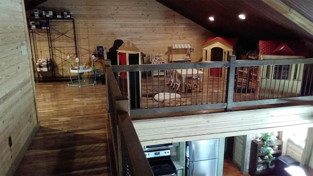 interior space with stainless steel fridge, wooden walls, and lofted ceiling