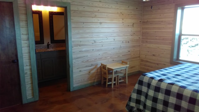 bedroom with dark hardwood / wood-style floors, sink, wooden walls, and connected bathroom