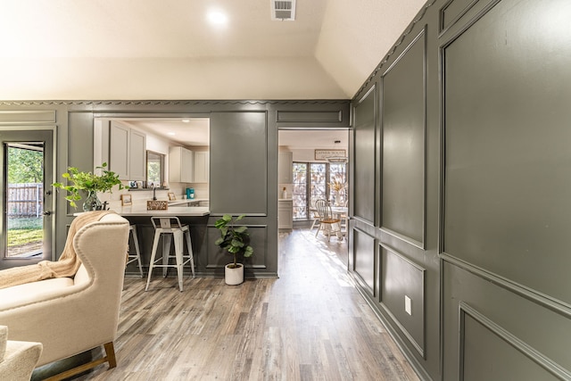 hallway with hardwood / wood-style floors, plenty of natural light, and lofted ceiling