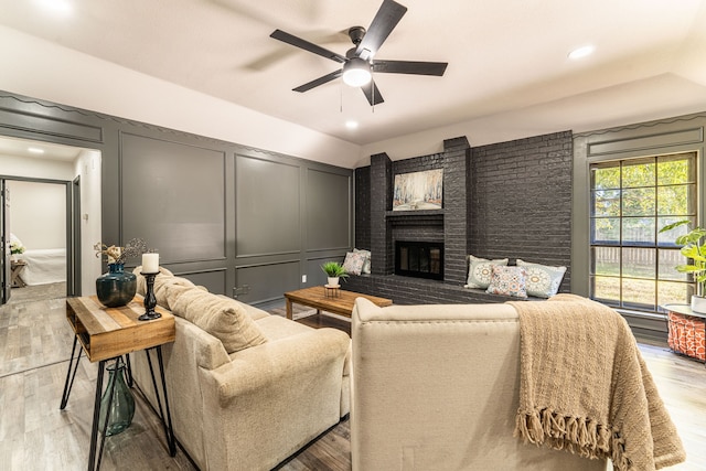 living room with ceiling fan, light hardwood / wood-style floors, and a fireplace