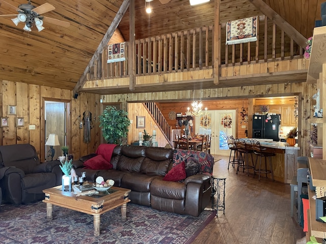 living room featuring wood walls, wooden ceiling, high vaulted ceiling, ceiling fan with notable chandelier, and dark hardwood / wood-style floors