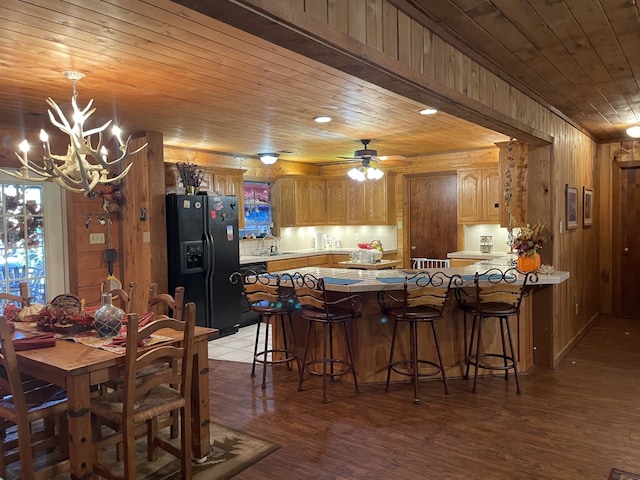 dining area with sink, light wood-type flooring, wooden ceiling, and wood walls