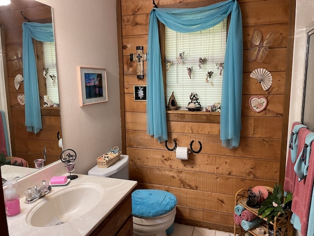 bathroom with tile patterned floors, wooden walls, vanity, and toilet