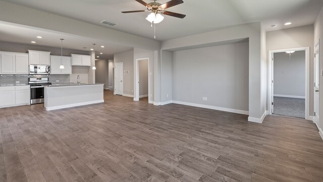 kitchen with hanging light fixtures, white cabinets, appliances with stainless steel finishes, a kitchen island, and light wood-type flooring