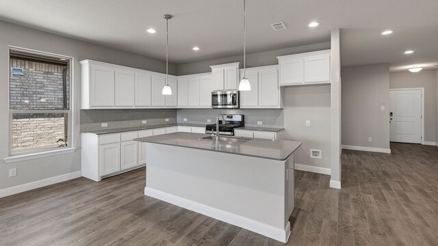 kitchen with an island with sink, dark hardwood / wood-style flooring, white cabinets, and stainless steel appliances