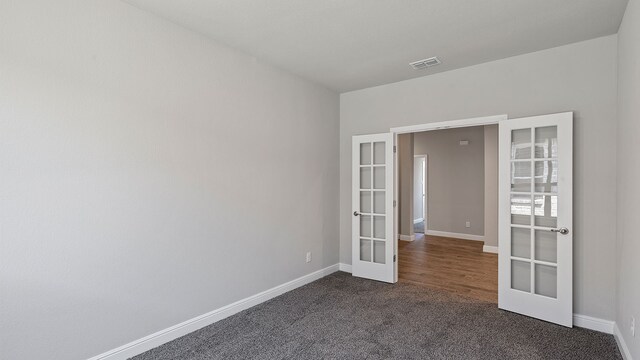 unfurnished room with dark carpet and french doors