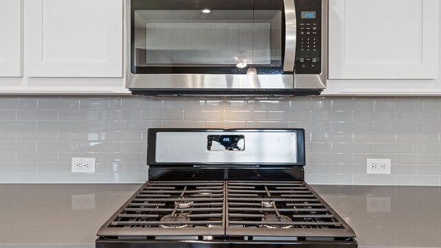 details with range, backsplash, and white cabinetry