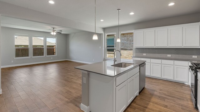 kitchen with sink, tasteful backsplash, a center island with sink, white cabinets, and appliances with stainless steel finishes