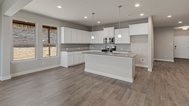 kitchen with a center island with sink, white cabinets, light hardwood / wood-style floors, and appliances with stainless steel finishes