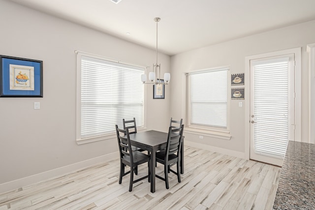 dining space with light wood-type flooring and an inviting chandelier