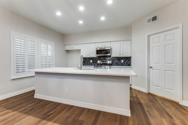 kitchen with white cabinetry, sink, dark hardwood / wood-style floors, a center island with sink, and appliances with stainless steel finishes