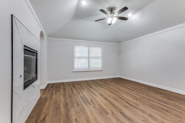 unfurnished living room with ornamental molding, vaulted ceiling, ceiling fan, dark wood-type flooring, and a fireplace