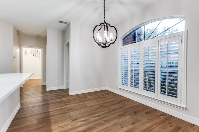 unfurnished dining area featuring a notable chandelier and dark hardwood / wood-style flooring