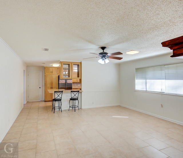 unfurnished living room featuring ceiling fan, crown molding, a textured ceiling, bar, and light tile patterned flooring