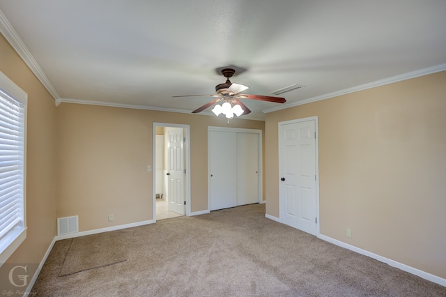 unfurnished bedroom featuring ceiling fan, crown molding, and light carpet