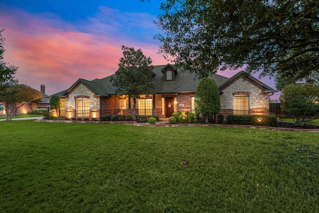 french country inspired facade featuring a lawn