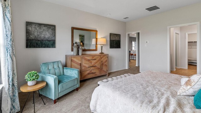 carpeted bedroom featuring a walk in closet and a closet