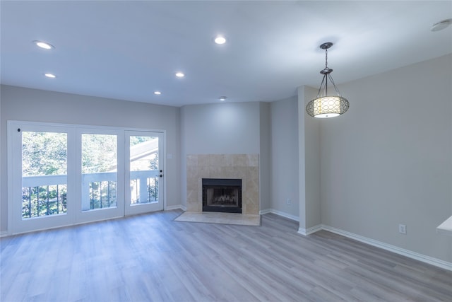 unfurnished living room with a tiled fireplace and light hardwood / wood-style flooring