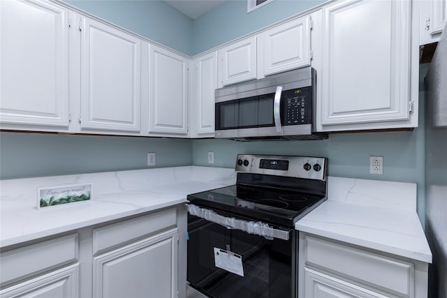 kitchen with white cabinetry, light stone countertops, and appliances with stainless steel finishes