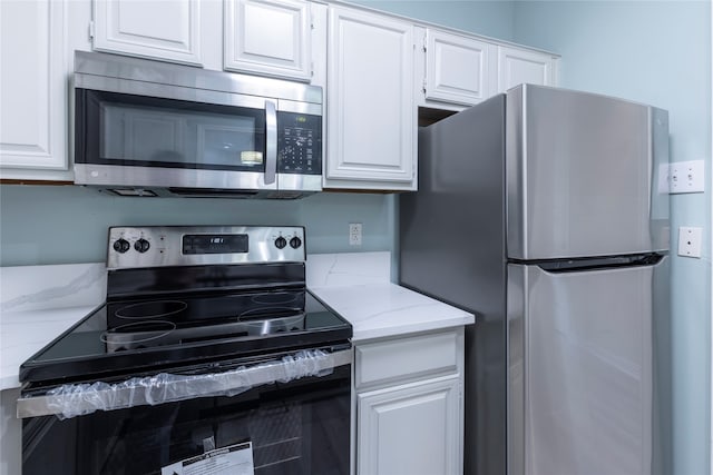 kitchen featuring white cabinets, light stone countertops, and stainless steel appliances